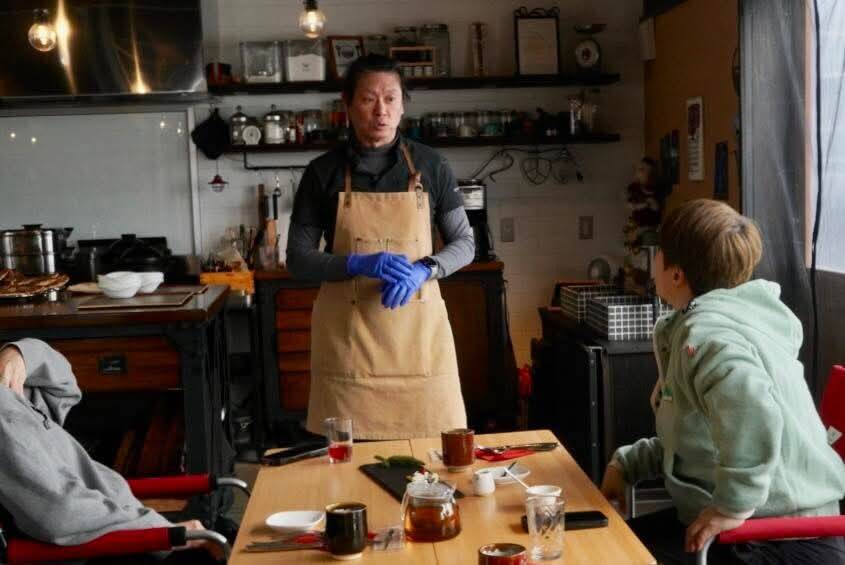 Ian 在廚房餐桌旁向賓客介紹食材